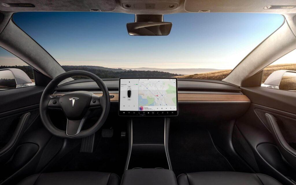 المقصورة الداخلية لسيارة Tesla Model 3 مع شاشة مركزية وتصميم بسيط حديث.