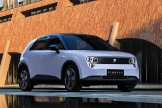 سيارة Nio Firefly 2025 الكهربائية بتصميم هاتشباك عصري متوقفة في شارع حضري حديث أمام مبنى زجاجي فاخر.