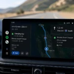 خرائط Google على شاشة Android Auto داخل سيارة كهربائية تعرض مسار رحلة طويل مع محطة شحن مقترحة ومستوى البطارية المتوقع أثناء القيادة.