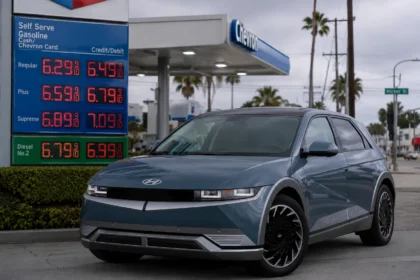 سيارة هيونداي Ioniq 5 الكهربائية متوقفة بجوار محطة وقود تعرض أسعار بنزين مرتفعة، في مشهد يعكس توجه المستهلكين نحو السيارات الكهربائية بسبب أزمة الوقود.