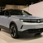 سيارة أوبل SUV كهربائية حديثة معروضة داخل صالة عرض بتصميم أوروبي وإضاءة LED أمامية وتقنيات كهربائية متطورة.