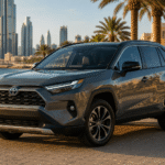 سيارة تويوتا RAV4 الهجينة باللون الرمادي في بيئة خليجية عصرية مع إطلالة بحرية وأبراج حديثة وقت الغروب