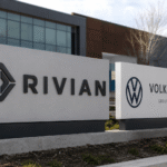 لافتات شركتي Rivian وVolkswagen أمام مبنى حديث في مشهد يعبر عن الشراكة والاستثمار في مستقبل السيارات الكهربائية.