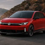 سيارة فولكس واجن GTI كهربائية حمراء بتصميم رياضي حديث تنطلق على طريق ساحلي جبلي مع أجواء سينمائية تعكس مستقبل سيارات الهاتشباك الكهربائية عالية الأداء.