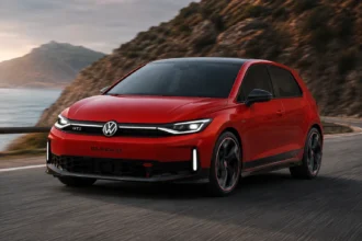 سيارة فولكس واجن GTI كهربائية حمراء بتصميم رياضي حديث تنطلق على طريق ساحلي جبلي مع أجواء سينمائية تعكس مستقبل سيارات الهاتشباك الكهربائية عالية الأداء.