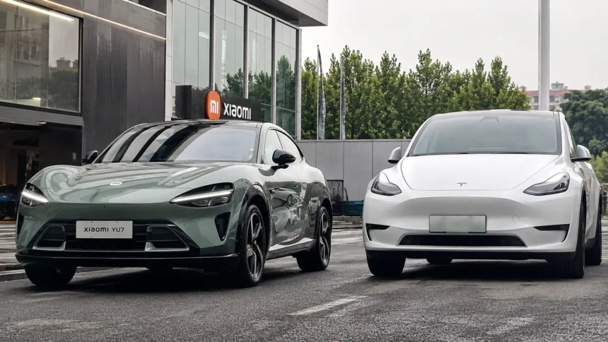 سيارة Xiaomi YU7 الكهربائية الجديدة بجانب Tesla Model Y أمام مبنى حديث في مقارنة توضح التصميم والمنافسة بين السيارتين الكهربائيتين.