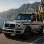 سيارة Mercedes Baby G-Class الكهربائية باللون الفضي أمام مصنع مرسيدس الحديث مع خطوط الإنتاج والروبوتات الصناعية، في مشهد يبرز بداية تصنيع أصغر نسخة من G-Class.